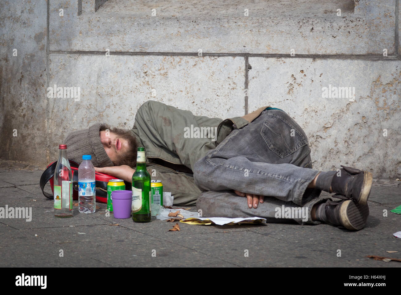 Berlin, Germany - Sept 18: Homeless young alcohol addict lying drunk on street sidewalk on 18th of September ,2016 in Berlin, Ge Stock Photo