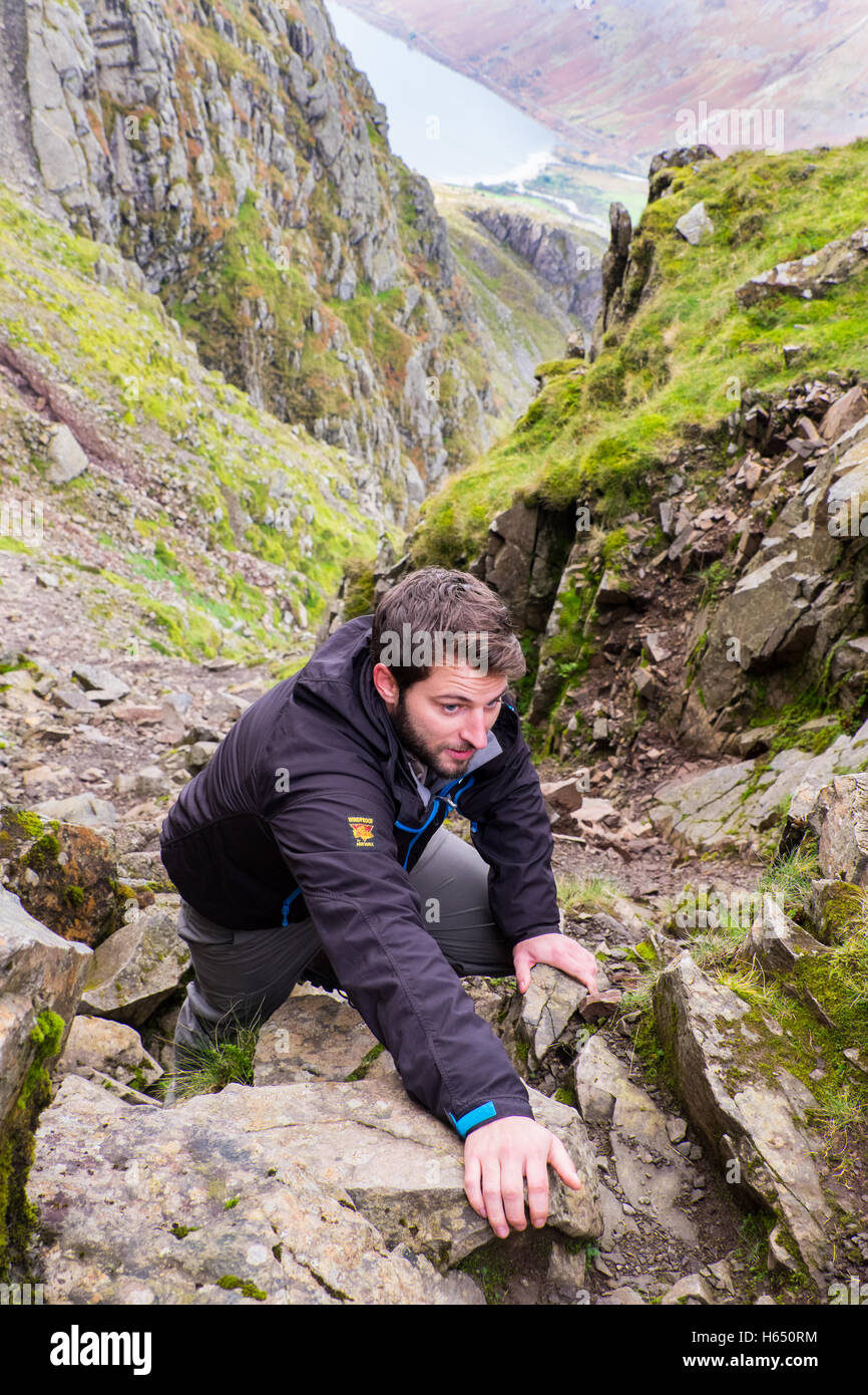 Male in his mid-twenties scrambling in Lord's Rake on Scafell,the Lake District, whilst wearing a Paramo jacket Stock Photo