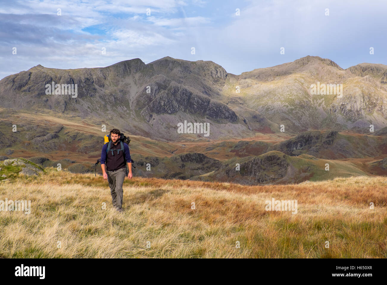 The Scafell group from Hardknott in the Lake District National Park. Male backpacker walking in foreground Stock Photo