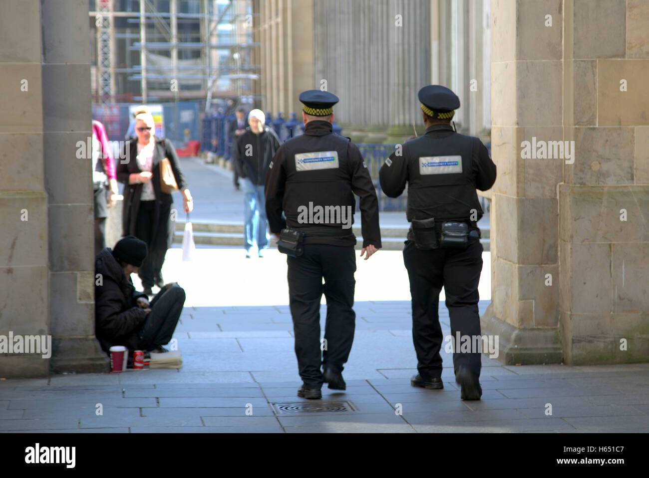Community officers on patrol with a beggar in background Stock Photo