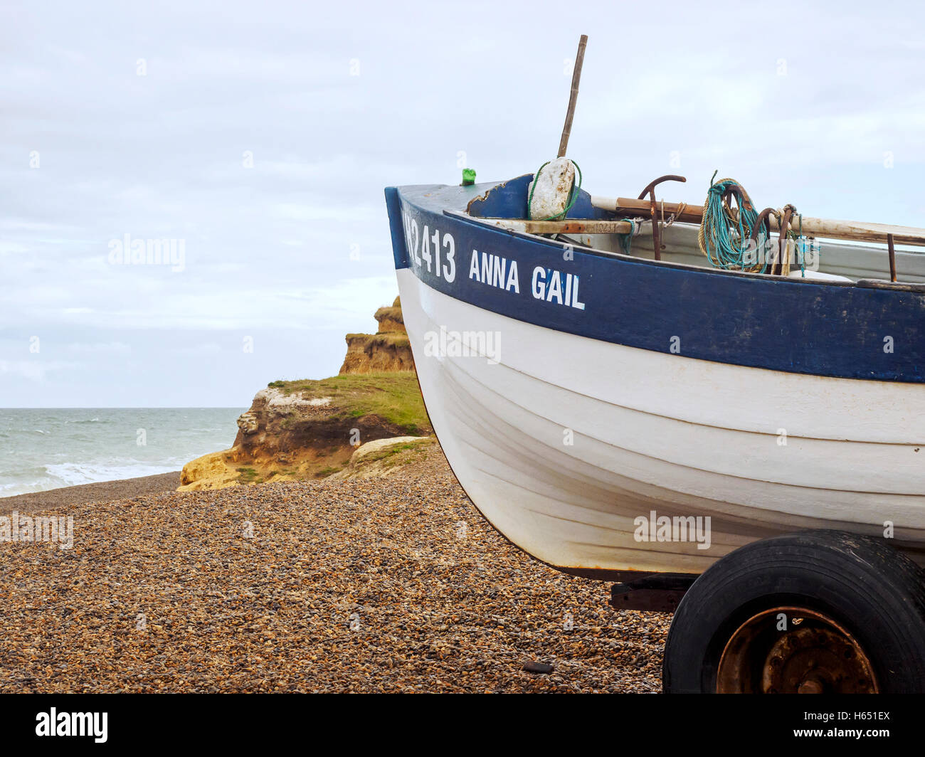 Traditional Norfolk crab boat hauled out on the shingle beach at Weybourne, Norfolk with eroding boulder clay cliffs behind Stock Photo