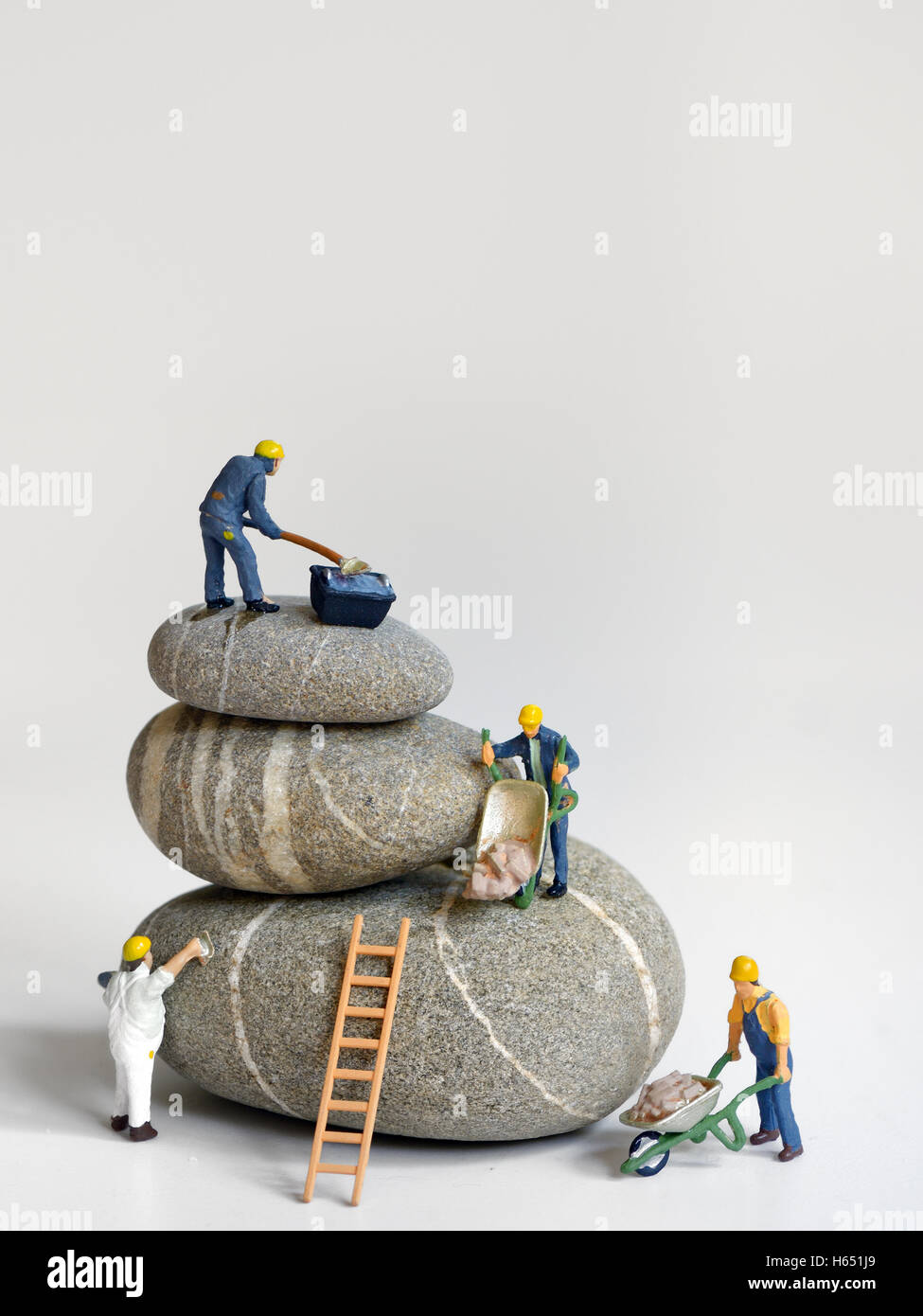 Pebbles stack and figurines of construction workers Stock Photo