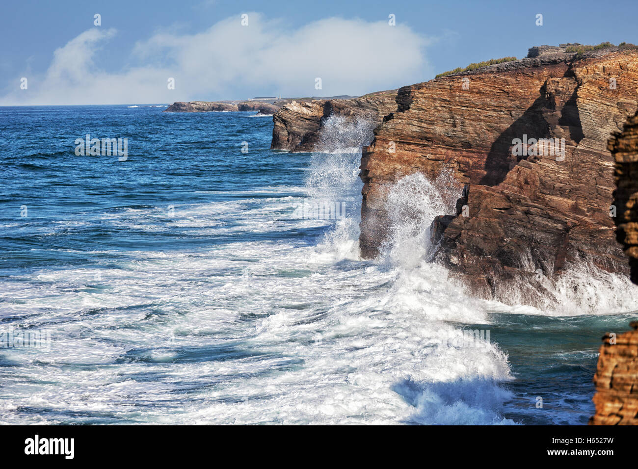 Oceanic waves break about coastal rocks Stock Photo