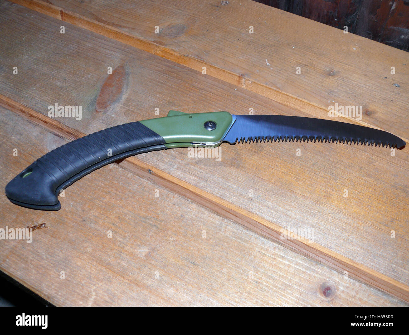 a pruning saw with green handle on wooden background Stock Photo