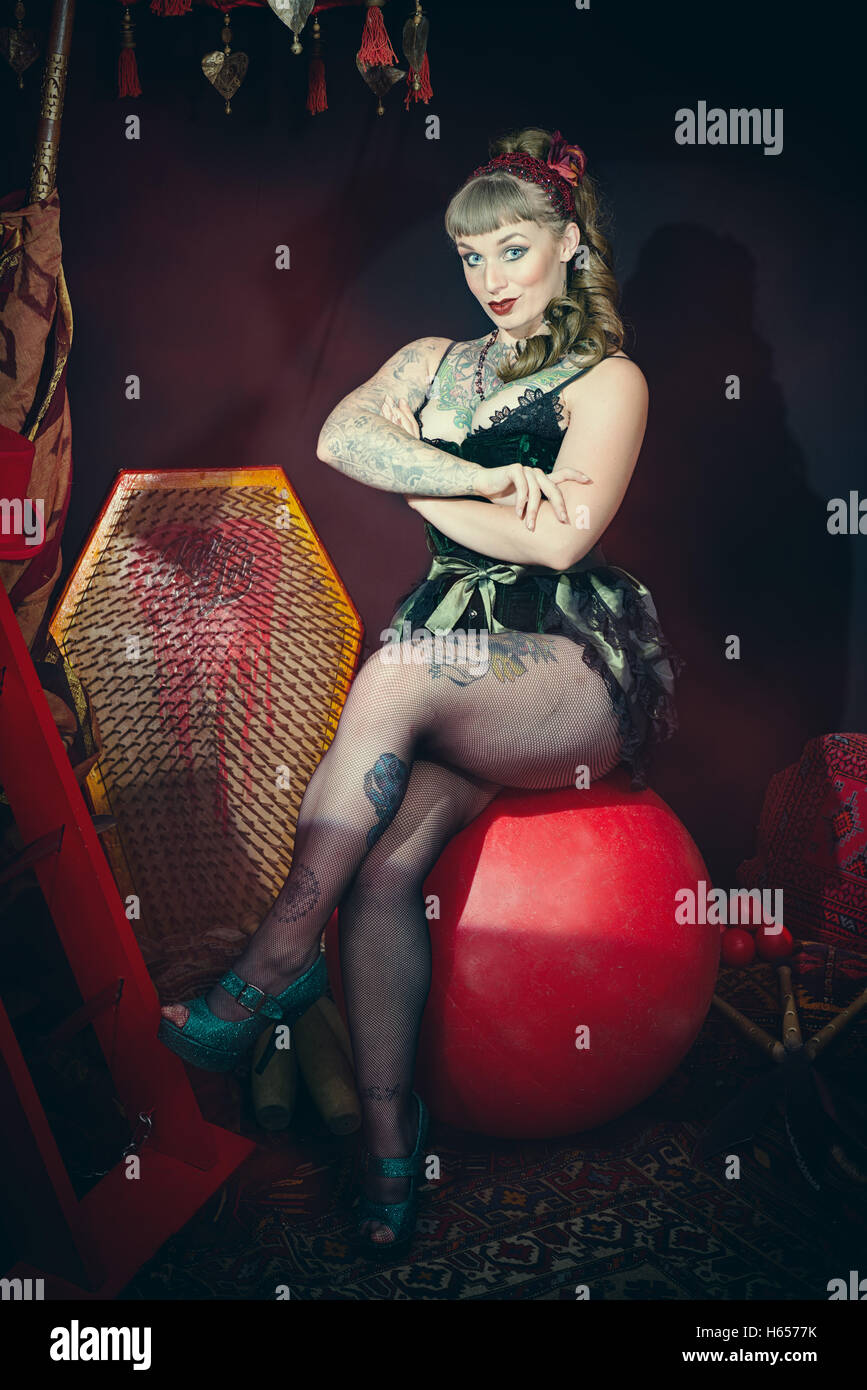Female circus performer sitting on giant ball Stock Photo
