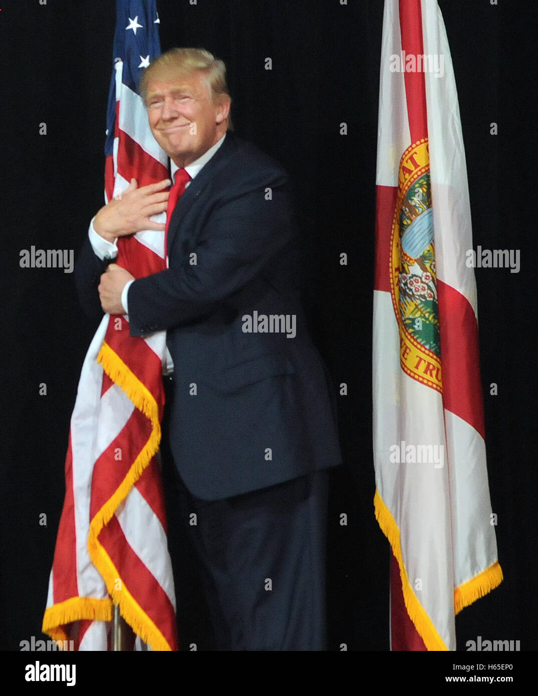 Tampa, Florida, USA. 24th Oct, 2016. Republican presidential nominee Donald Trump hugs an American flag as he takes the stage to speak at a campaign rally at the MidFlorida Credit Union Amphitheatre in Tampa, Florida, the third of five cities Trump is visiting during a two-day campaign swing through Florida. Credit:  Paul Hennessy/Alamy Live News Stock Photo