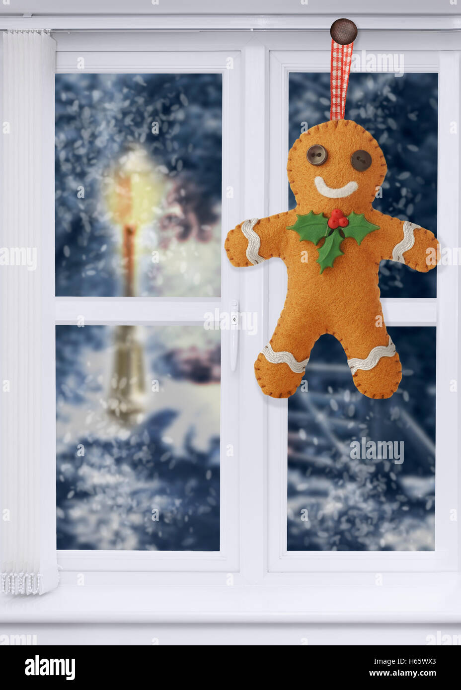 Gingerbread man decoration hanging in the window with snow scene outside Stock Photo