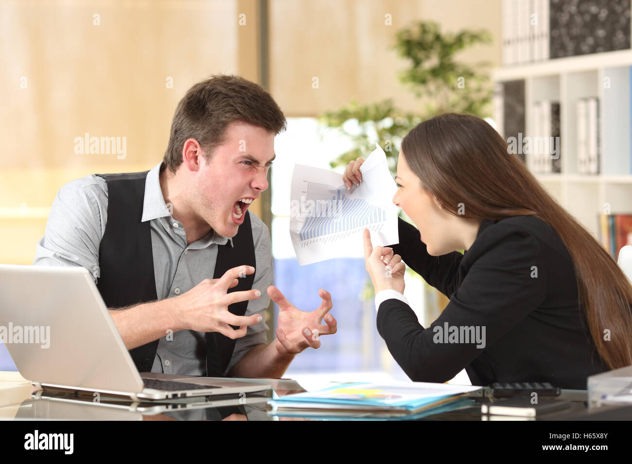 Two angry businesspeople arguing furious showing a negative growth graph at office Stock Photo