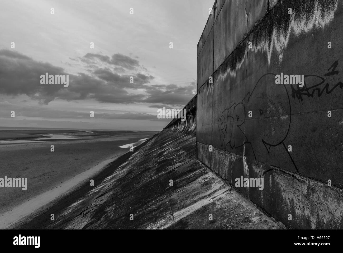 Dark, moody sea wall at sunset in Blackpool, England during autumn while the famous Black Illuminations are lit up Stock Photo