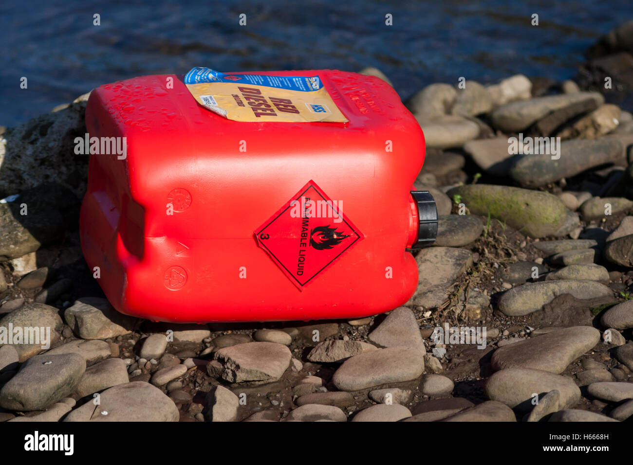 fuel drum polluting river bank Stock Photo