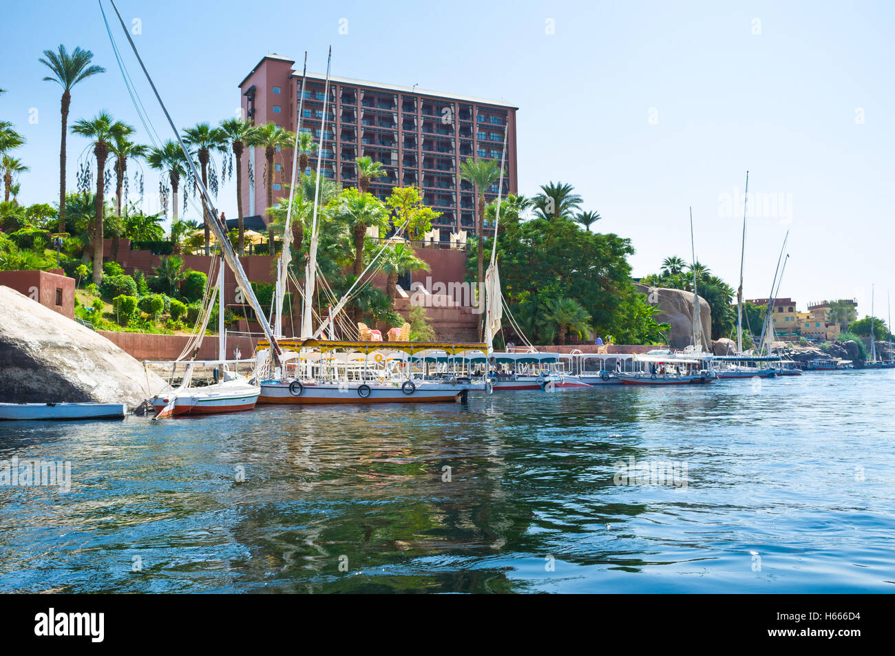 The luxury hotel on the Nile promenade with the numerous boats and feluccas, moored at wharf, Aswan, Egypt. Stock Photo