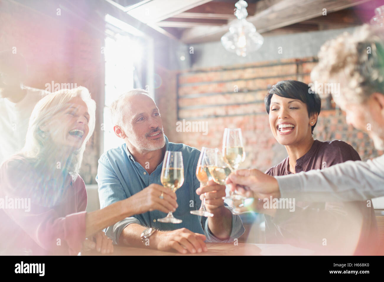 Friends toasting white wine glasses at restaurant table Stock Photo