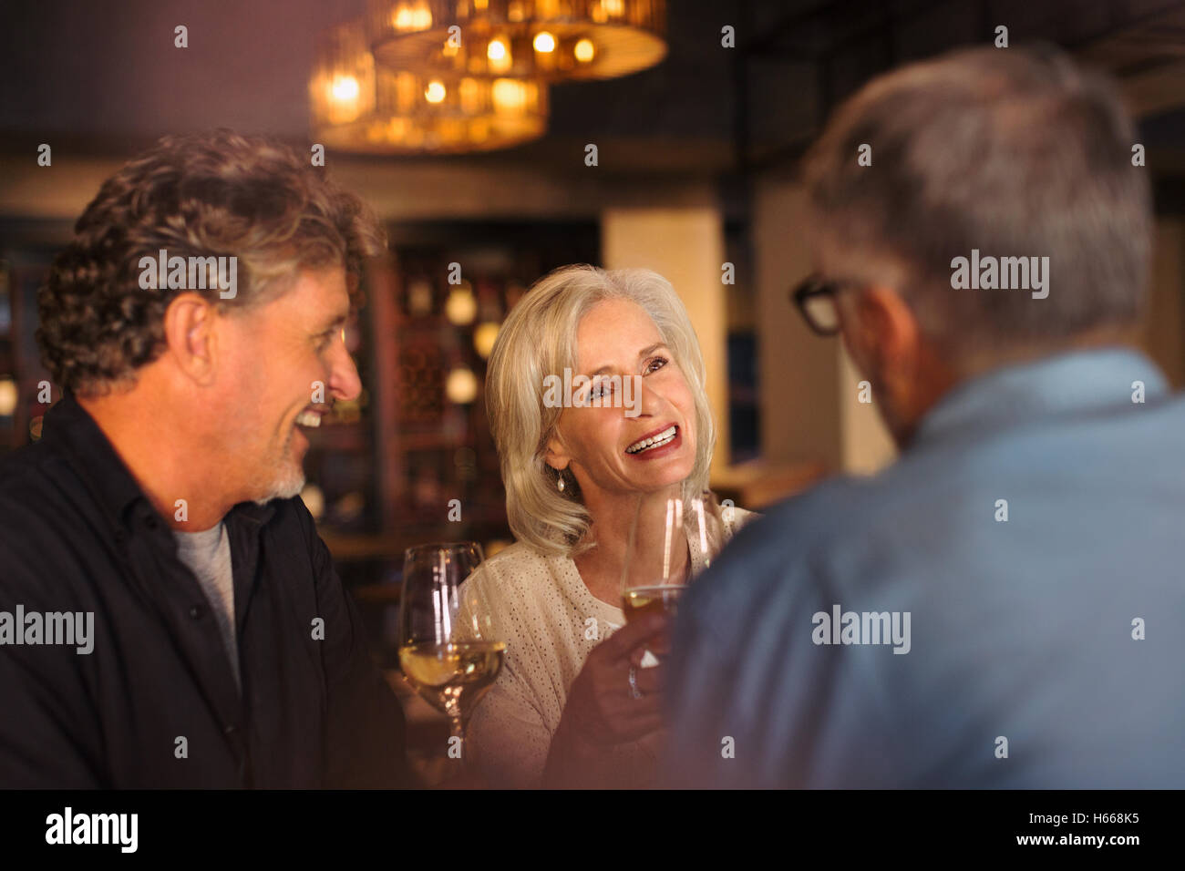 Friends drinking white wine and talking in restaurant Stock Photo