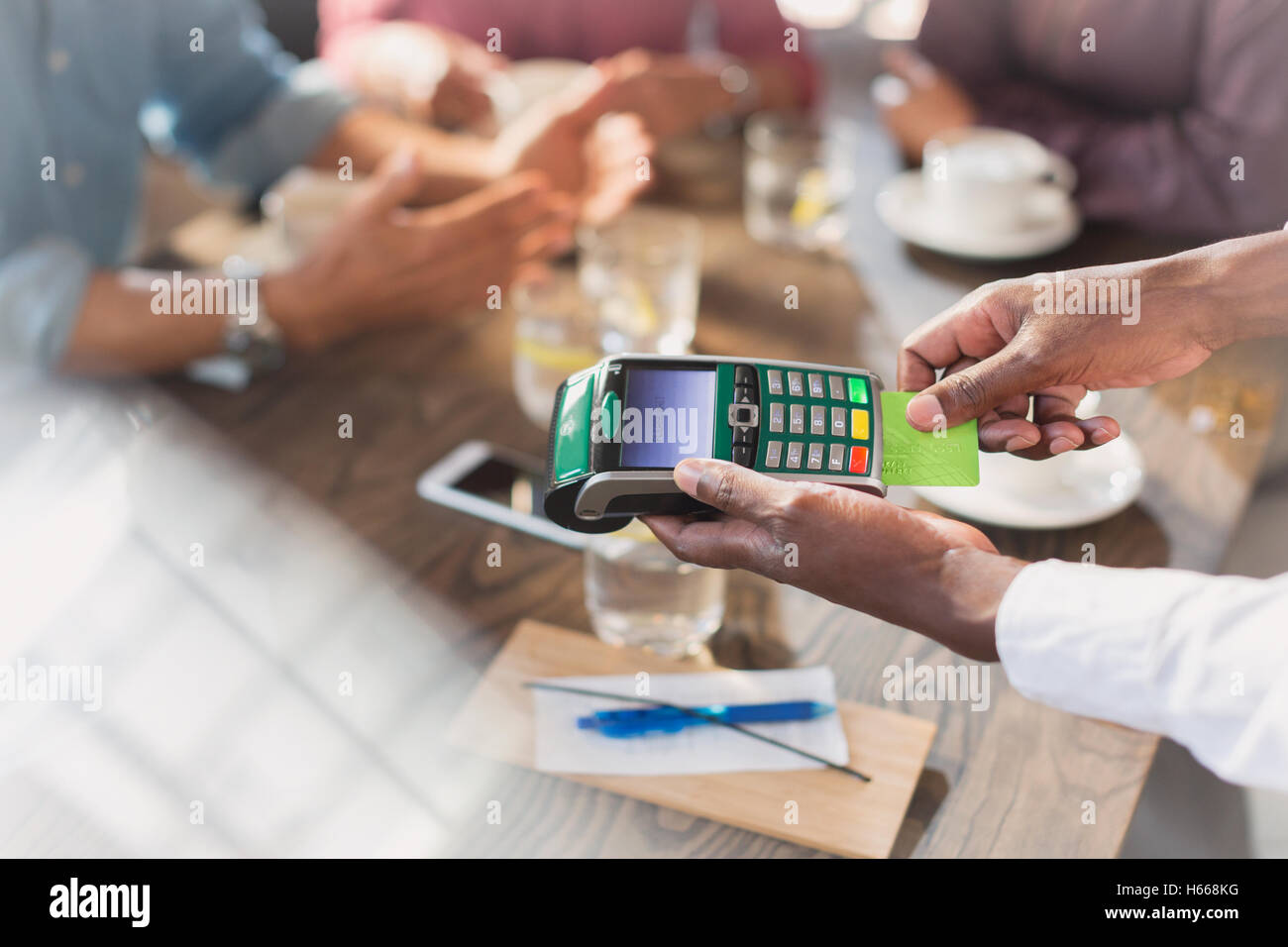 Waiter using credit card reader at restaurant table Stock Photo Alamy