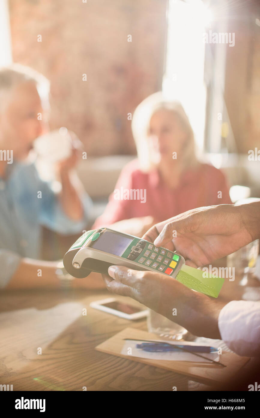 Waiter using credit card reader at restaurant table Stock Photo Alamy