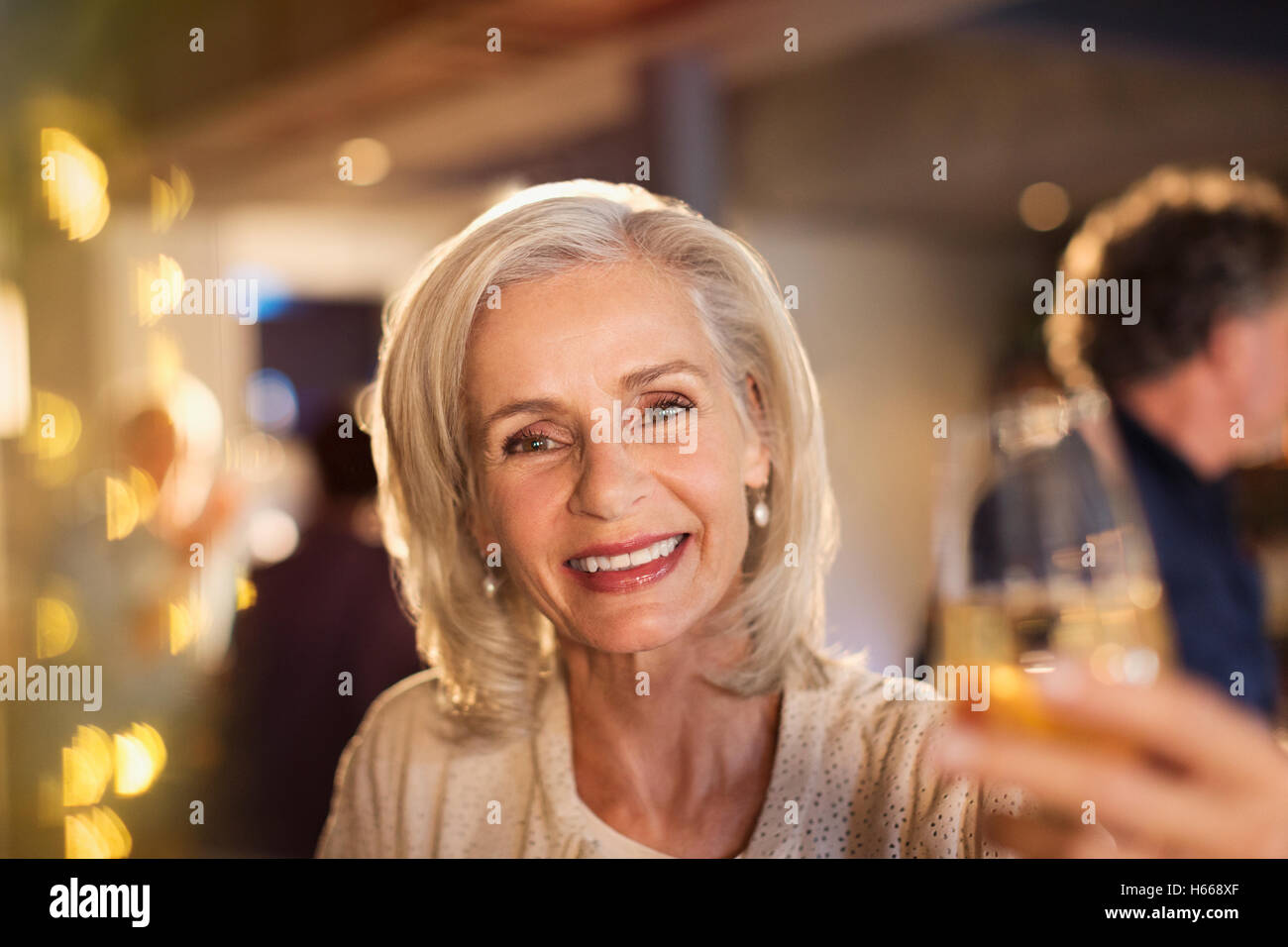 Portrait smiling senior woman toasting white wine glass at bar Stock Photo