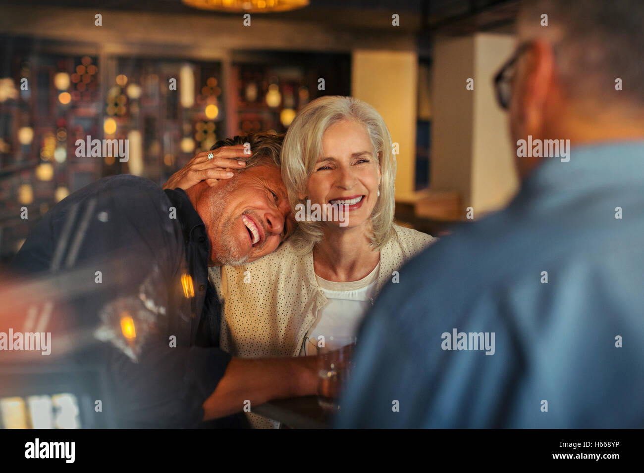 Affectionate senior couple laughing and hugging in bar Stock Photo