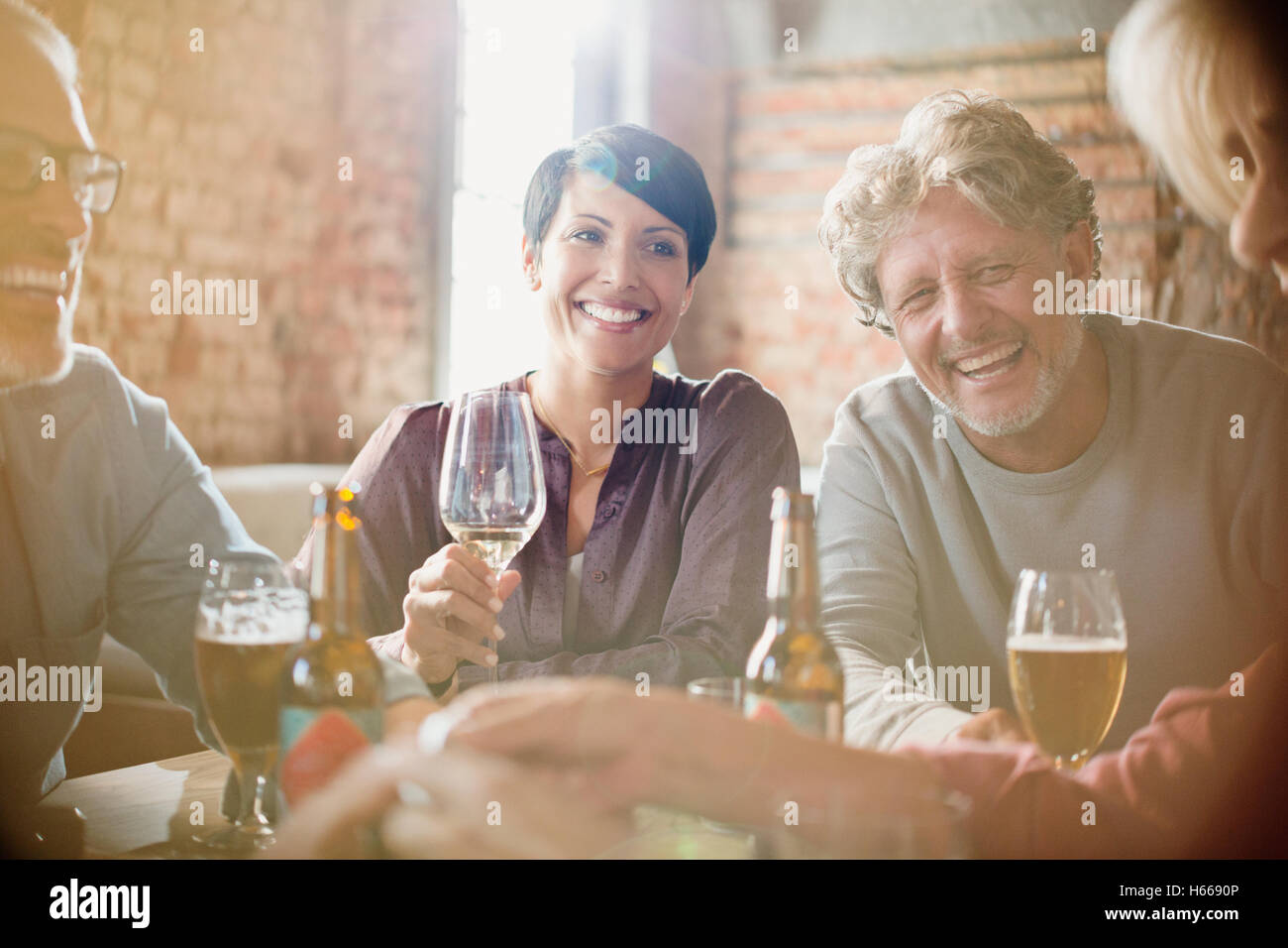 Laughing couples drinking white wine and beer at restaurant table Stock Photo