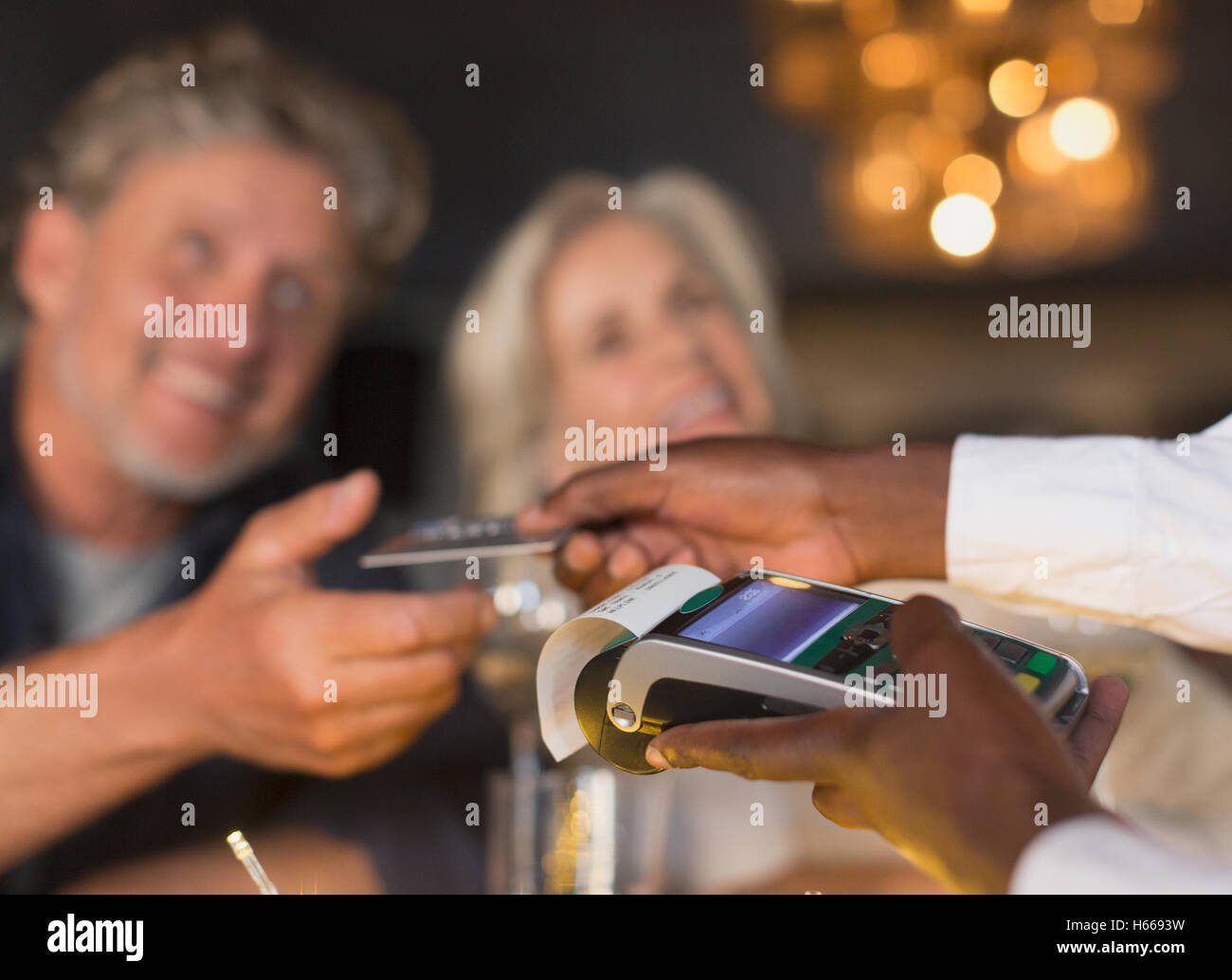 Close up waiter using credit card machine returning credit card to couple Stock Photo