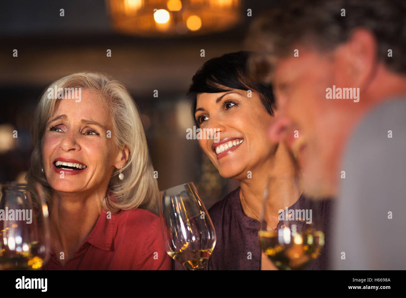 Smiling women drinking white wine at bar Stock Photo