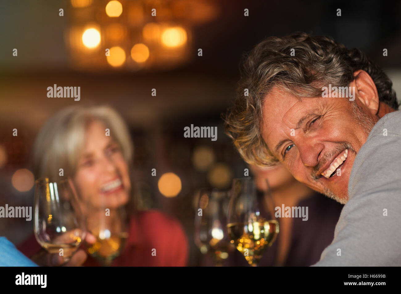 Portrait laughing senior man drinking white wine with friends at bar Stock Photo