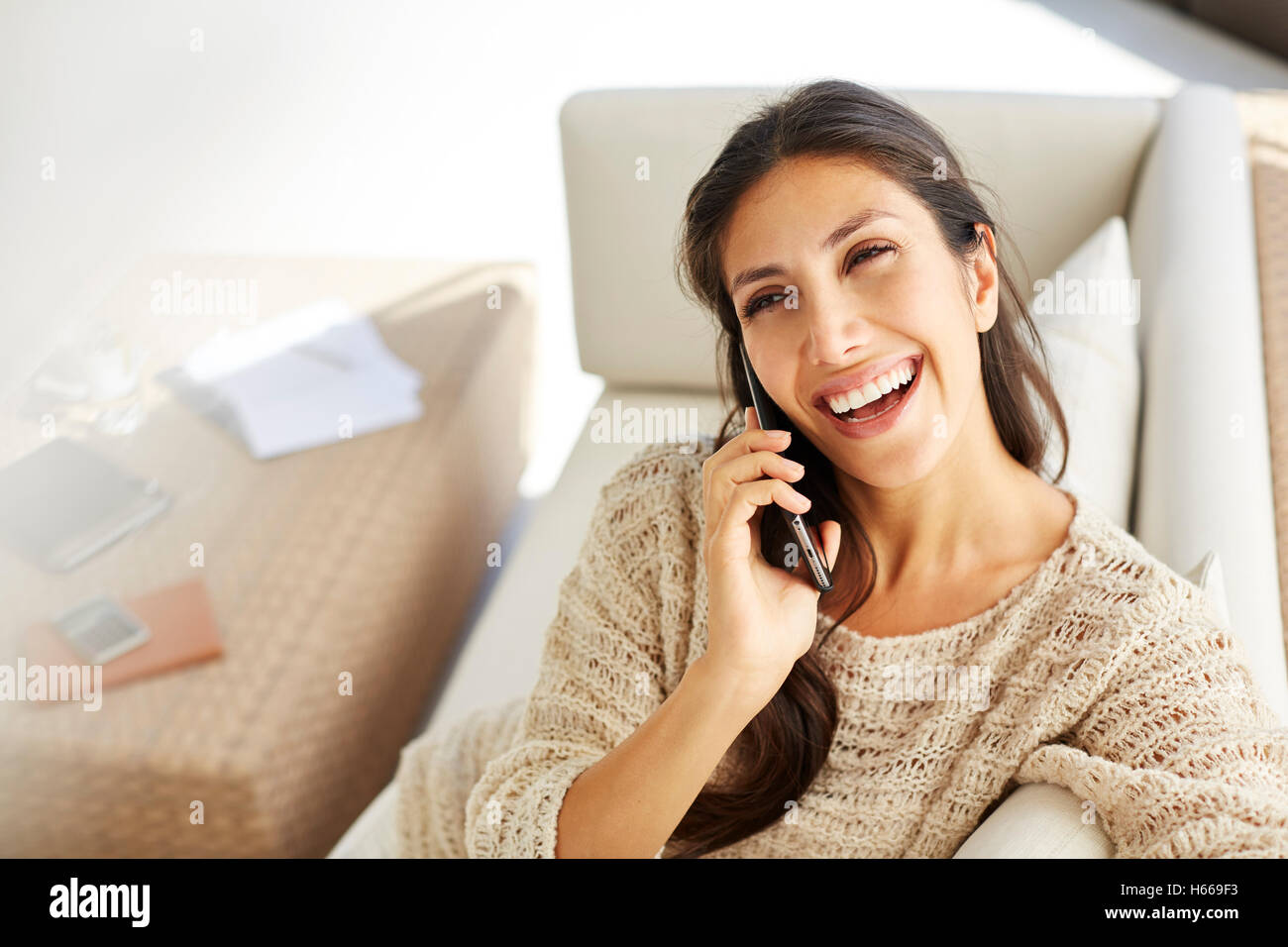 Laughing woman talking on cell phone on sofa Stock Photo