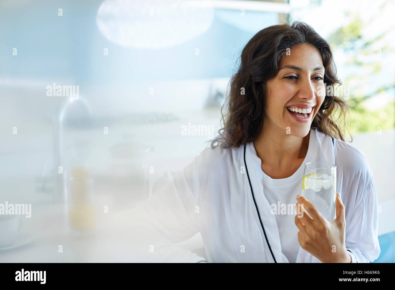 Laughing woman in bathrobe drinking water Stock Photo