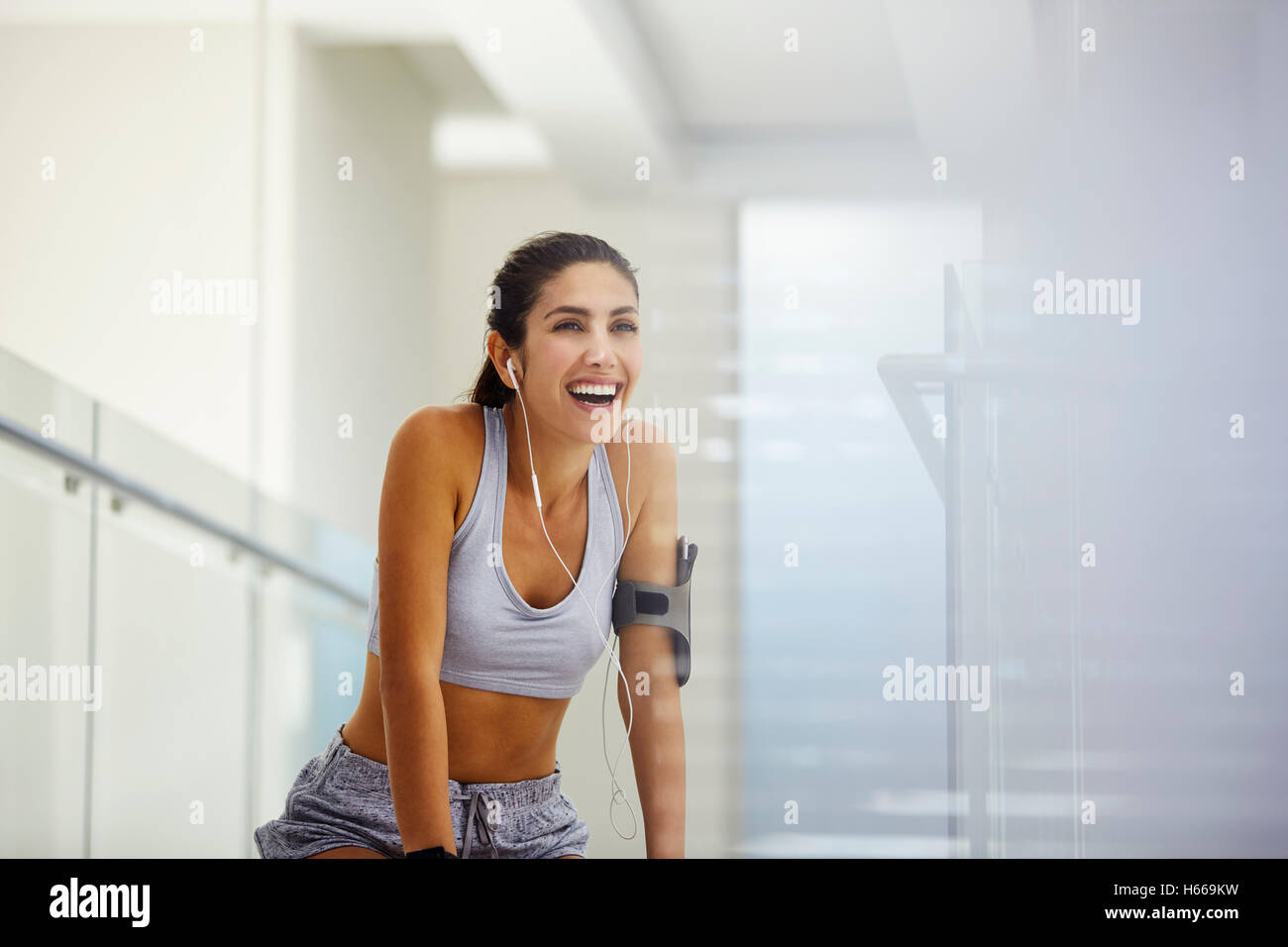Enthusiastic woman with armband listening to music with headphones post workout Stock Photo
