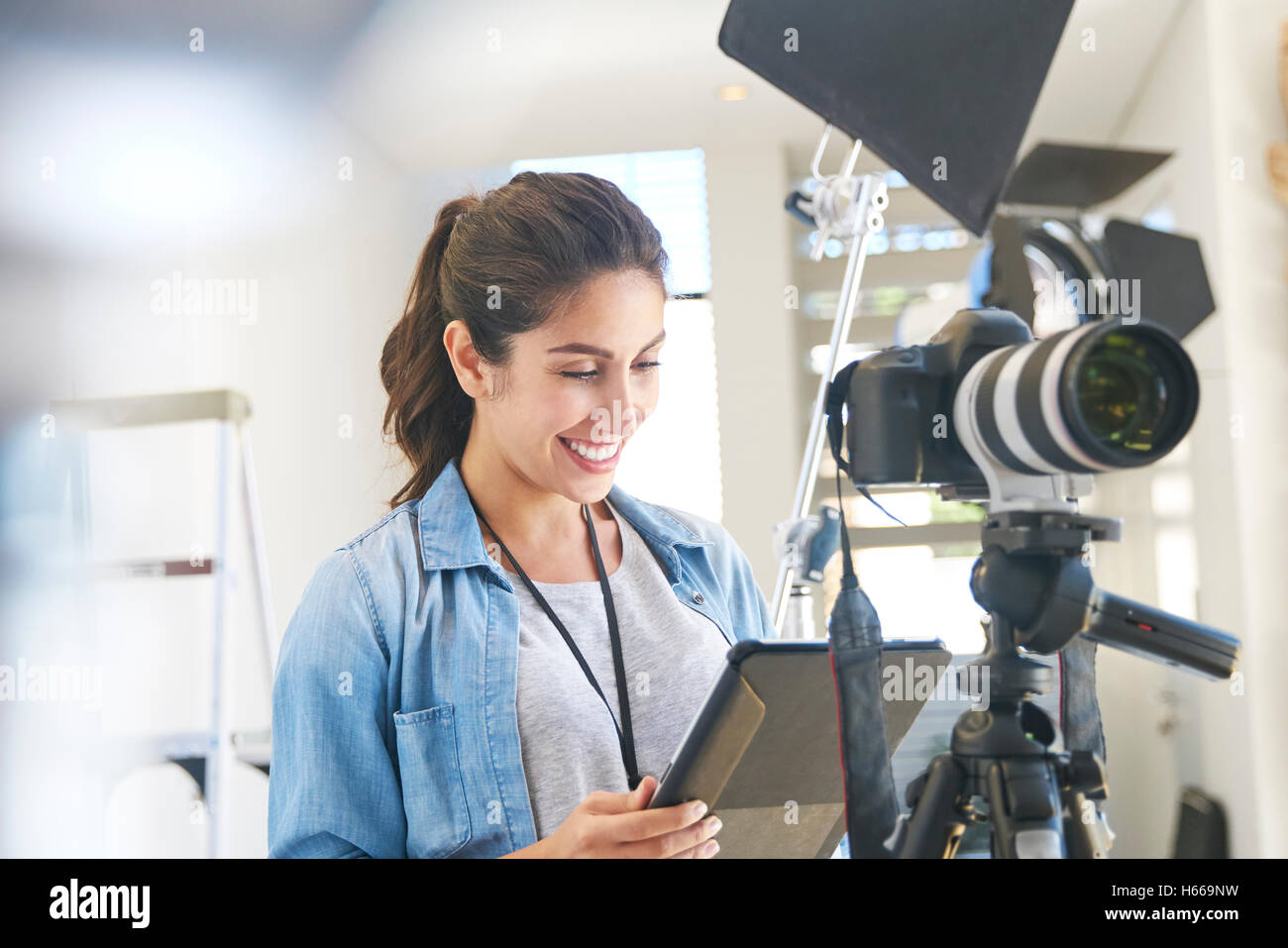 Female photographer using digital tablet behind camera in studio Stock Photo