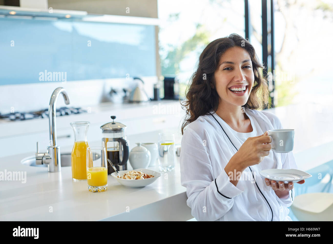 Portrait laughing woman in bathrobe drinking coffee in morning kitchen Stock Photo