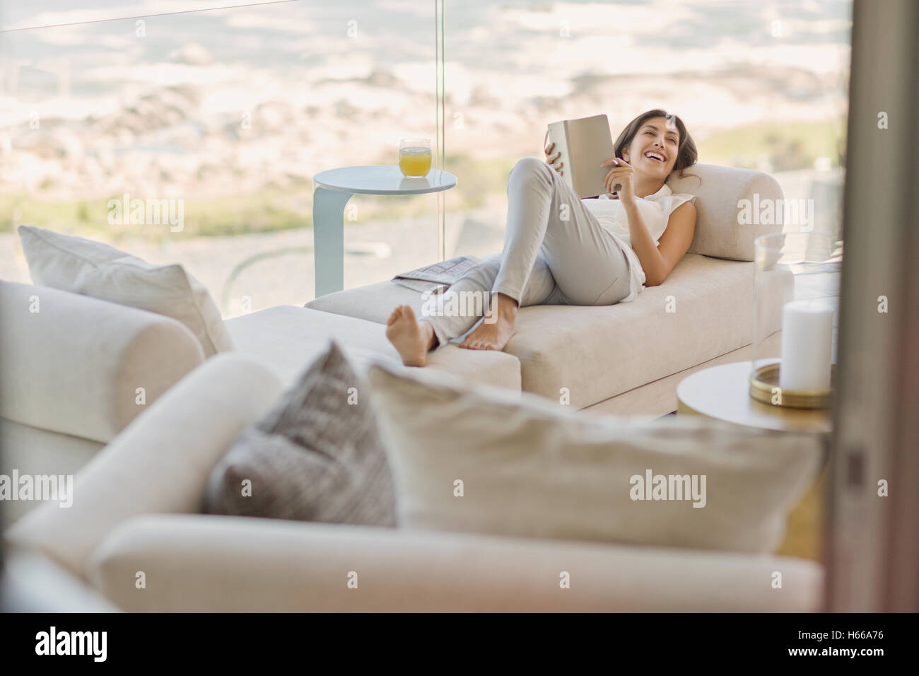 Smiling woman reading book relaxing on chaise lounge Stock Photo