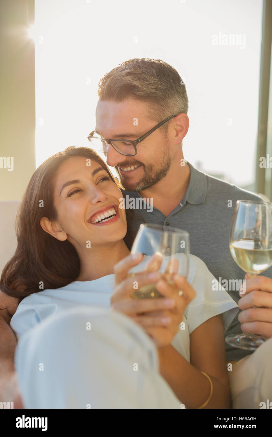 Affectionate couple smiling and drinking white wine Stock Photo