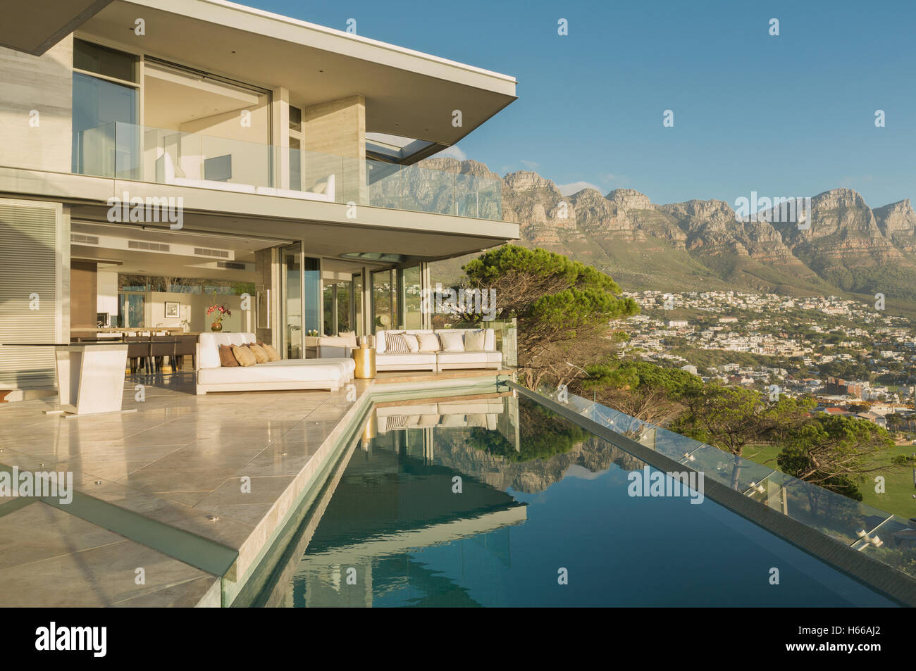 Sunny modern luxury home showcase exterior with lap pool and mountain ...