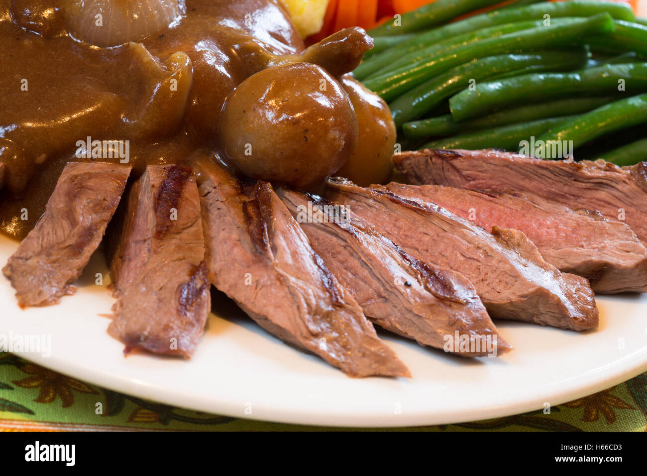 A dish of Seared Venison Steak with mash potato green bean, carrots and topped with whole