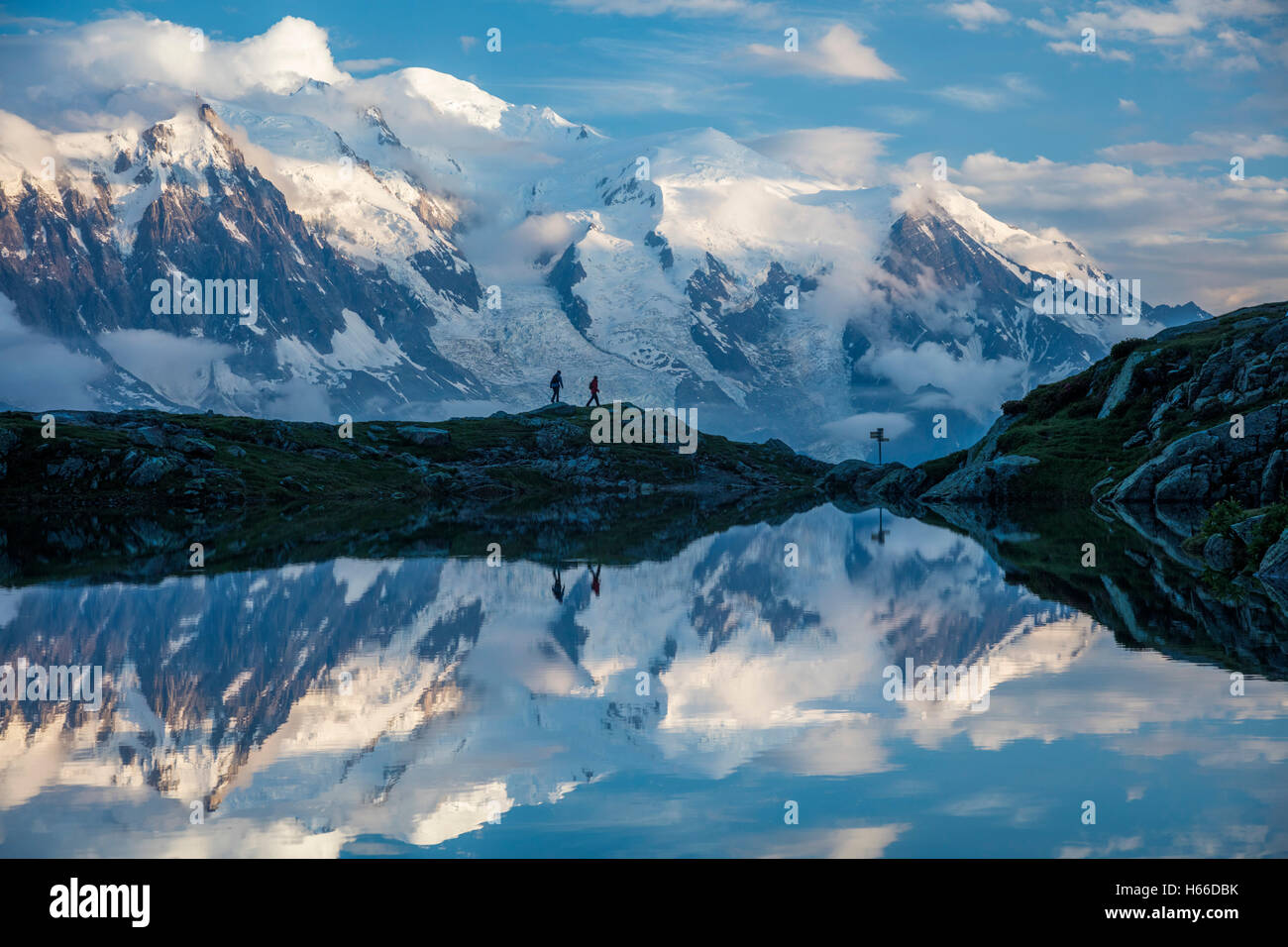 Hikers and the Mont Blanc massif reflected in Lac des Cheserys. Chamonix Valley, French Alps, France. Stock Photo