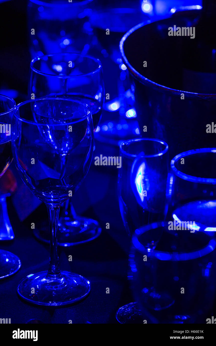 A table full of glasses and wine bottles at an awards ceremony lit by