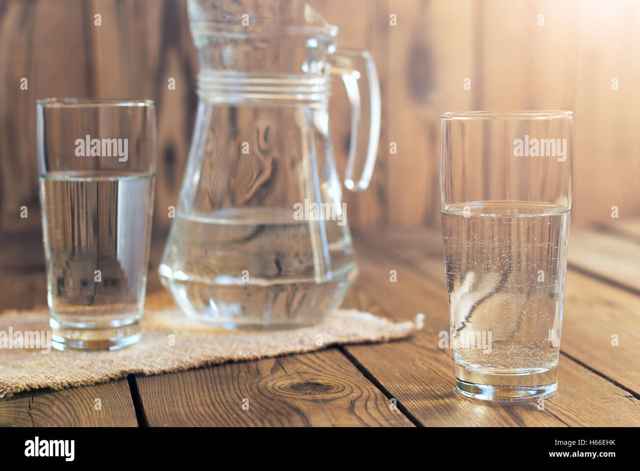 Glasses of water on a wooden table. Selective focus. Shallow DOF. With lighting effects. Stock Photo