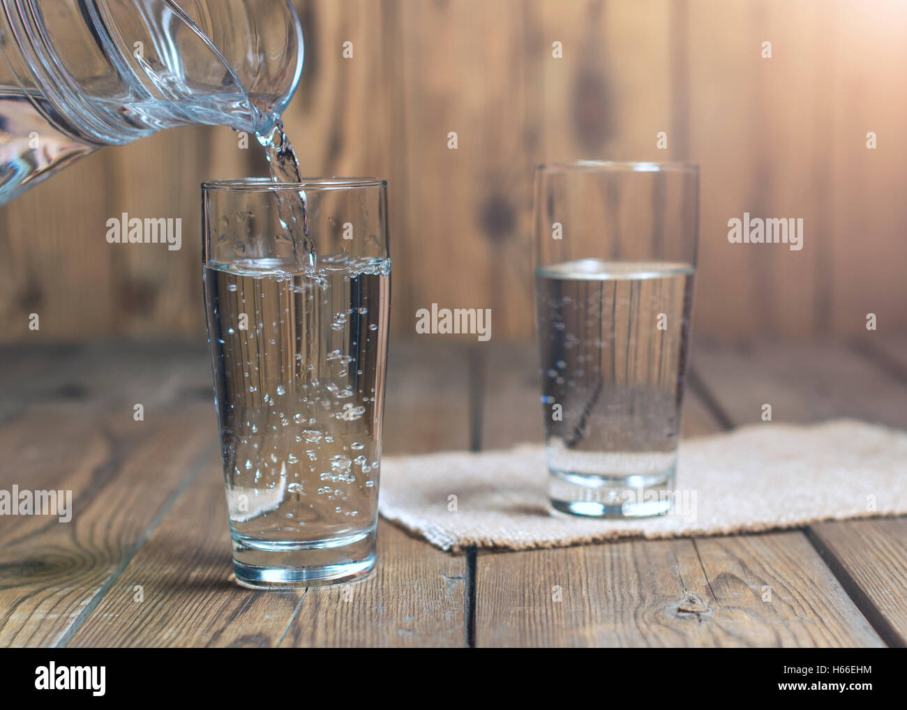 Glasses of water on a wooden table. Water was poured into the beaker. Selective focus. Shallow DOF. With lighting effects. Stock Photo