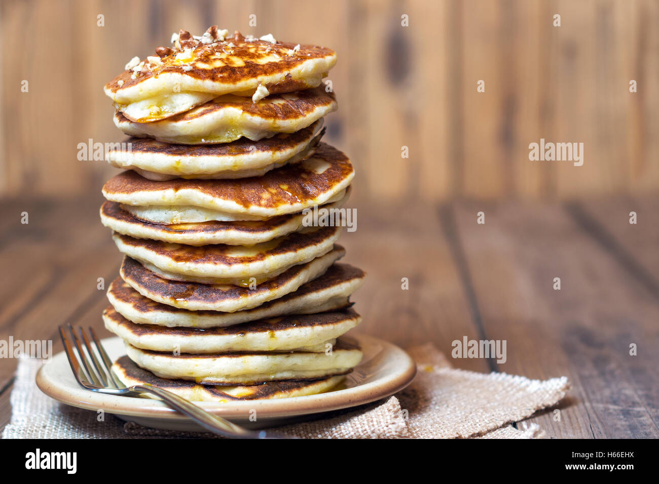 High stack of pancakes with syrup and walnuts on top. The rustic style. With copy space. Shallow DOF Stock Photo