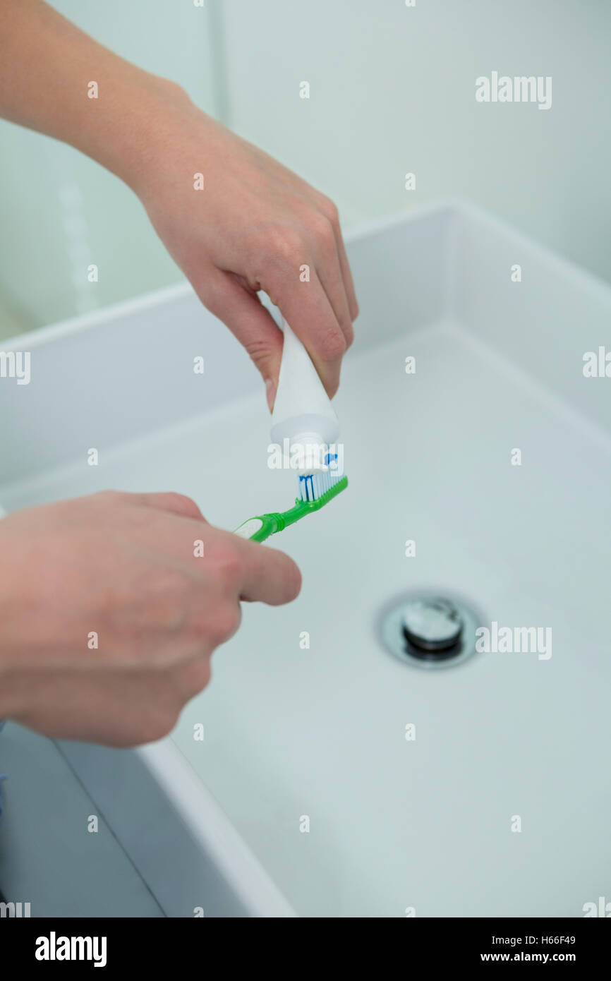Woman putting toothpaste on brush in bathroom Stock Photo