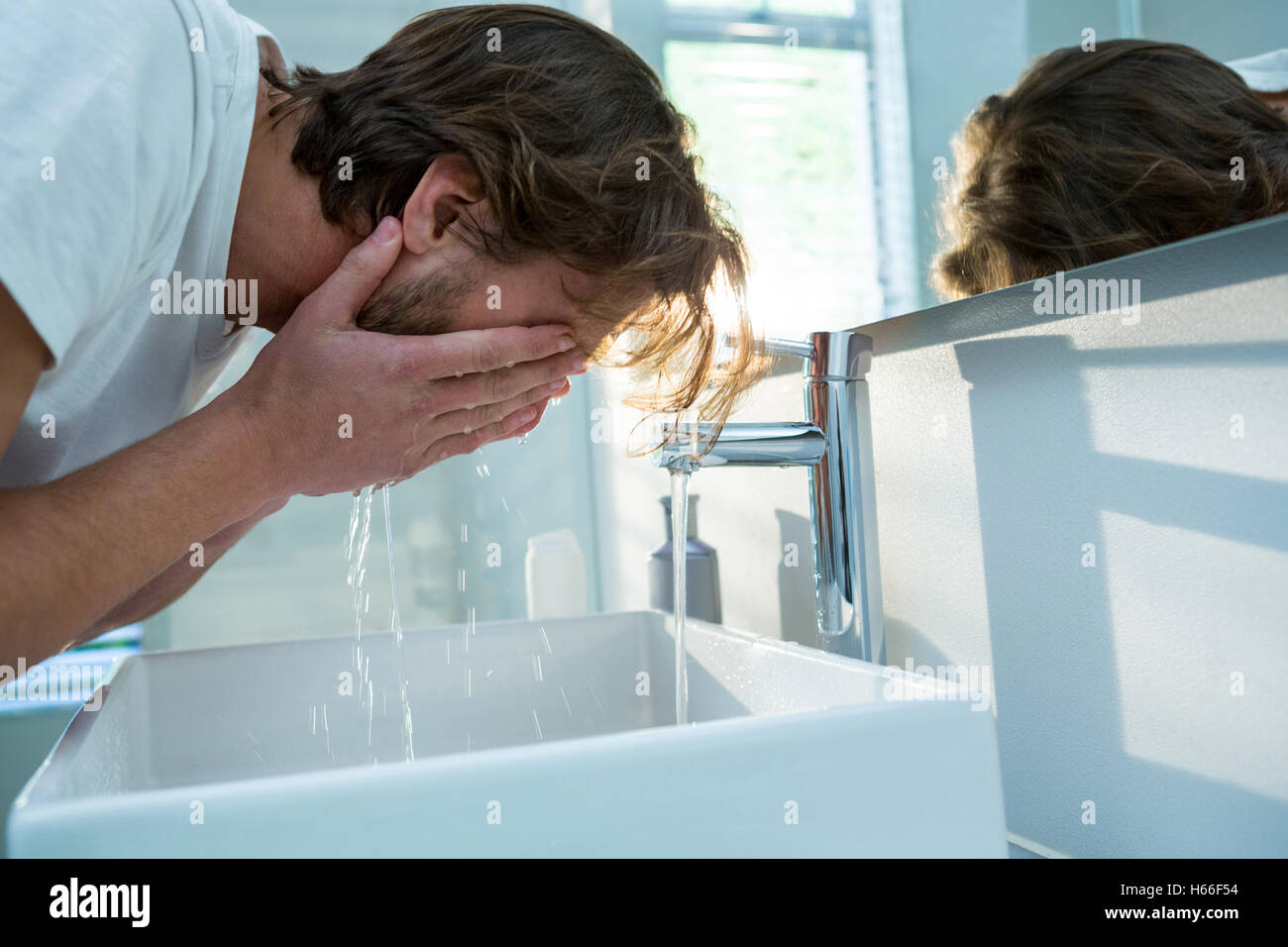 Man washing his face with water in bathroom Stock Photo
