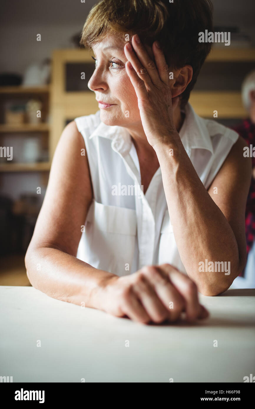 Worried senior woman leaning on table Stock Photo