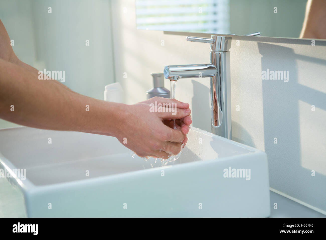 Man washing his hands in bathroom sink Stock Photo