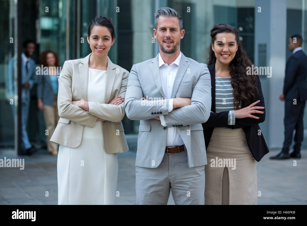 Smiling businesspeople standing with arms crossed in office building Stock Photo