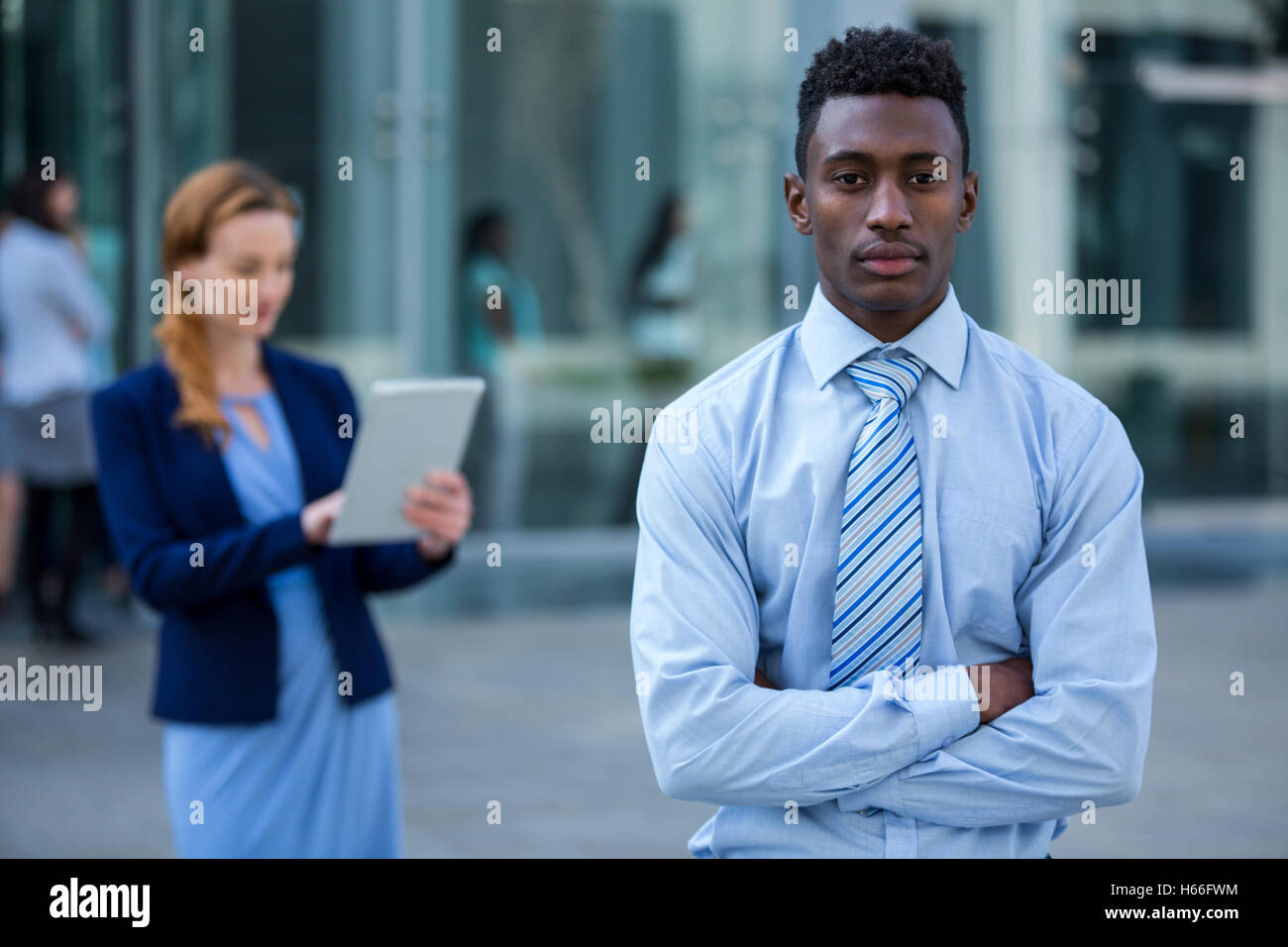 Businessman standing with arms crossed in office building Stock Photo ...