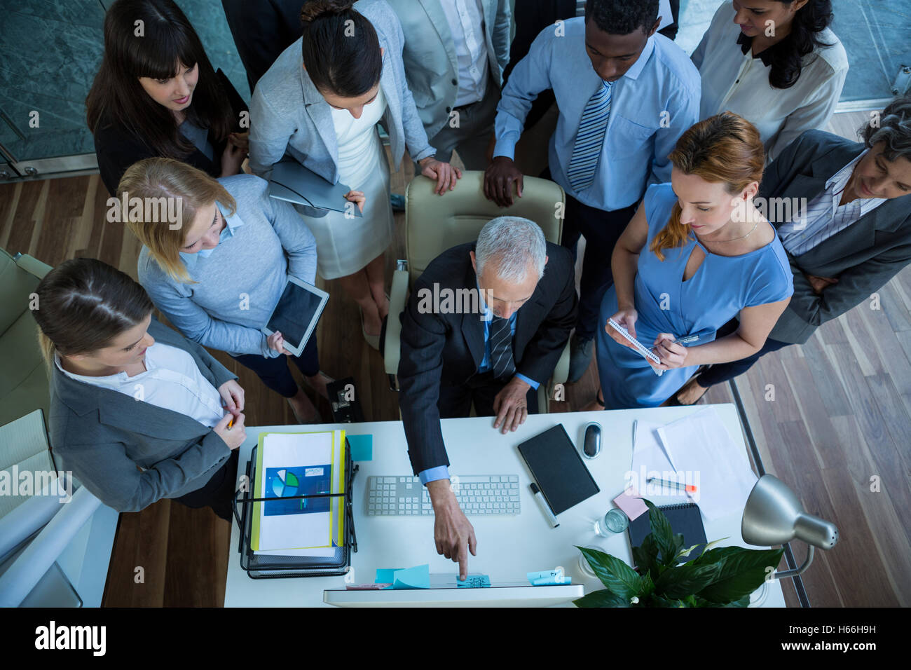 Businessman discussing with colleagues over computer Stock Photo