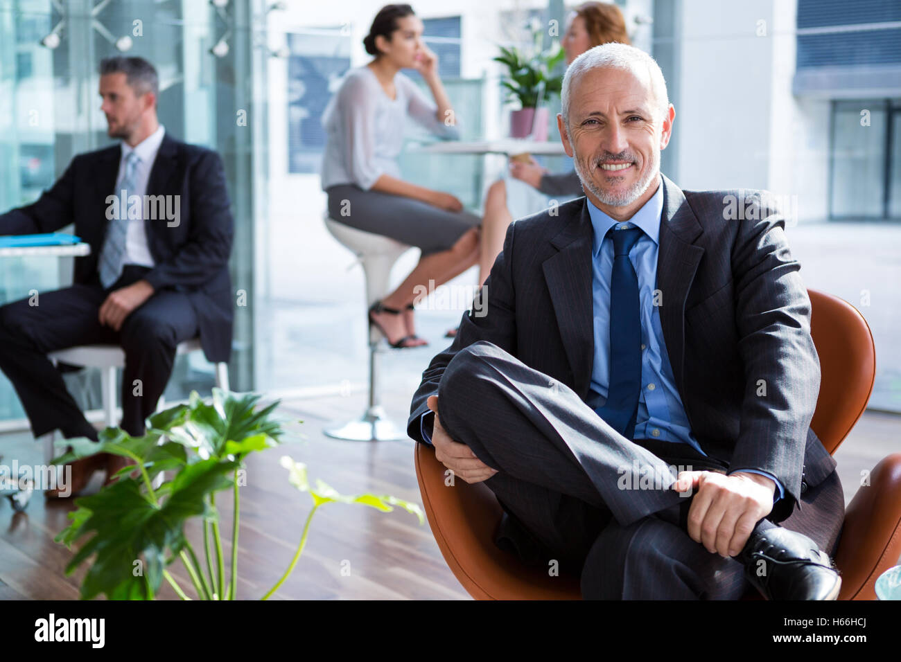 Smiling businessman sitting on chair in office Stock Photo