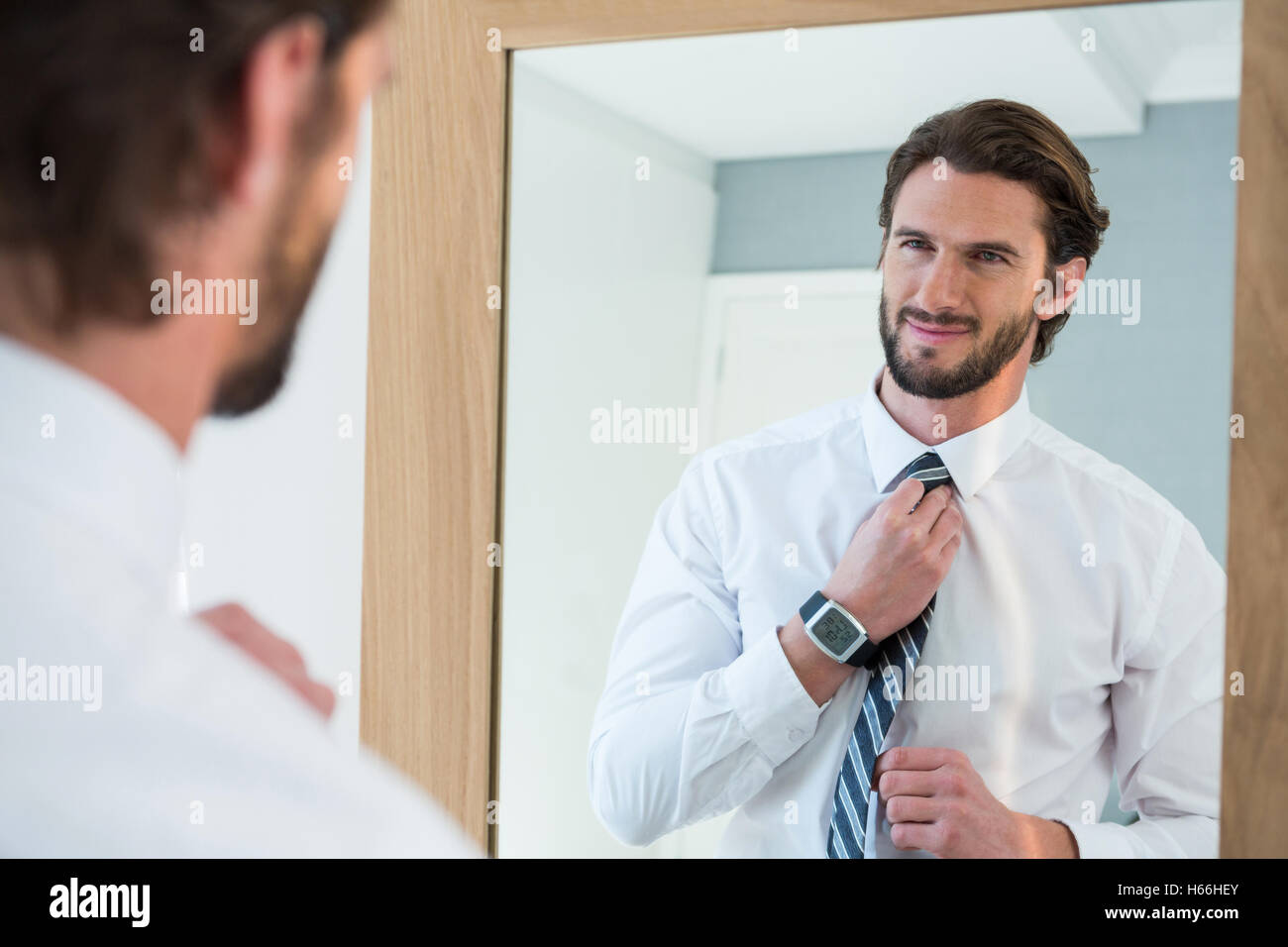 Man getting dressed in bedroom while looking at mirror Stock Photo Alamy