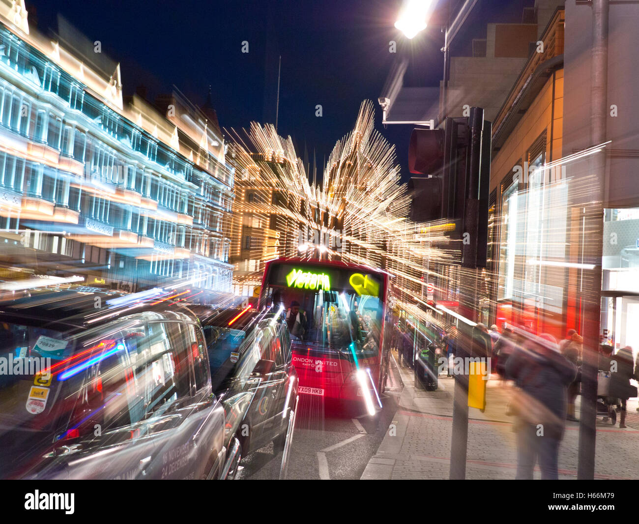 Action Shopping Bonanza Harrods and Knightsbridge department stores at dusk shoppers red bus and busy traffic with 'action zoom effect' in camera applied  Knightsbridge London SW1 Stock Photo