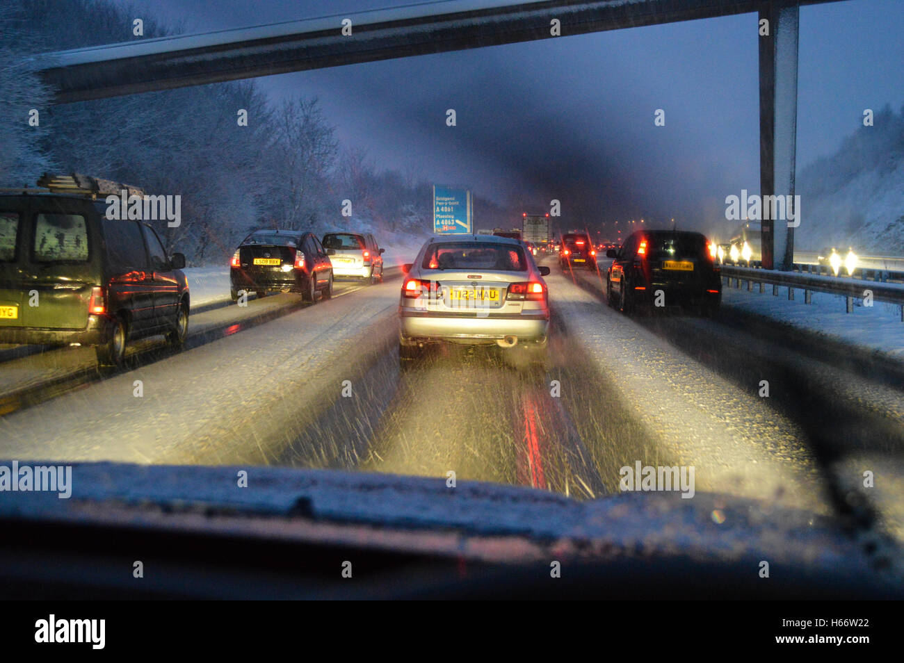 Vehicles creating tracks in falling snow in the evening on the M4 Motorway in South Wales, UK Stock Photo